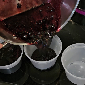 pouring mixed berry jam into freezer-safe containers