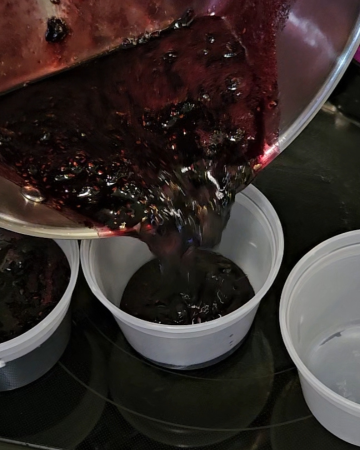 pouring mixed berry jam into freezer-safe containers