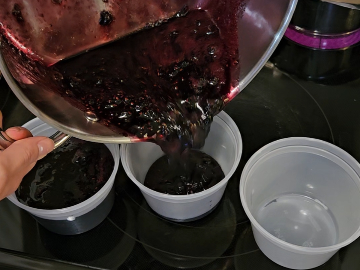 pouring mixed berry jam into freezer-safe containers